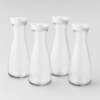 Four tall, clear glass bottles with white caps arranged together against a light gray background.