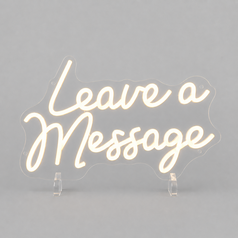 Neon sign that reads 'Leave a Message' in cursive, mounted on a gray backdrop with clear stands nearby (decorative display).