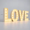 Giant illuminated LOVE marquee letters with warm bulbs, 120 cm tall, on a light floor.